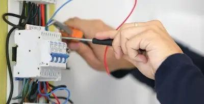 Electrician installing and adjusting circuit breakers in an electrical panel in Fresno, CA
