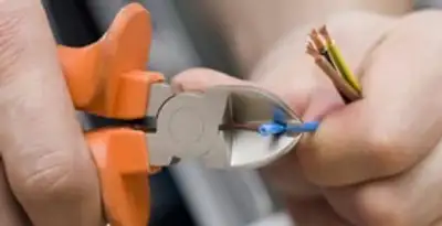 licensed electrician performing precise wire cutting and preparation during electrical service in Fresno, CA