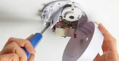Certified technician wiring smoke detector during installation in Fresno, CA